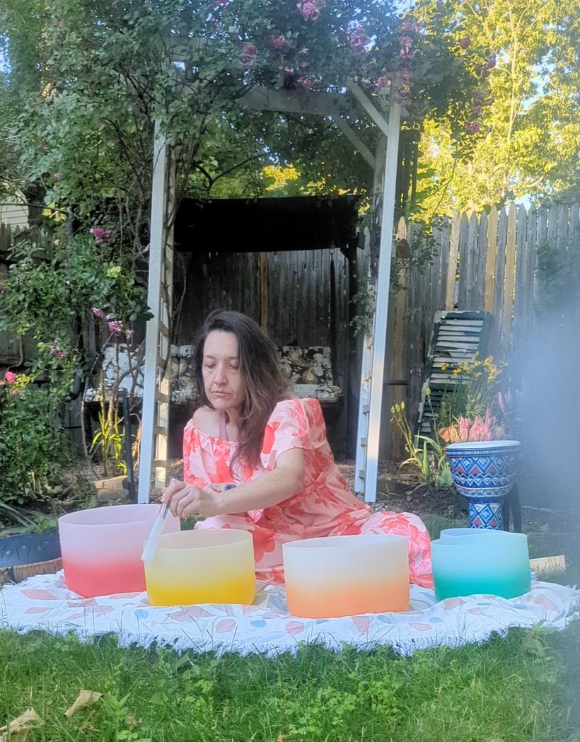 Kendra playing crystal singing bowls in her garden